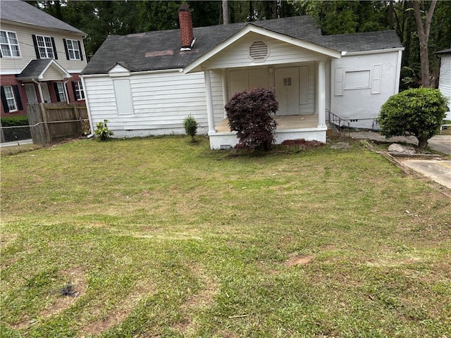exterior space featuring fence, a shingled roof, a front yard, a chimney, and covered porch