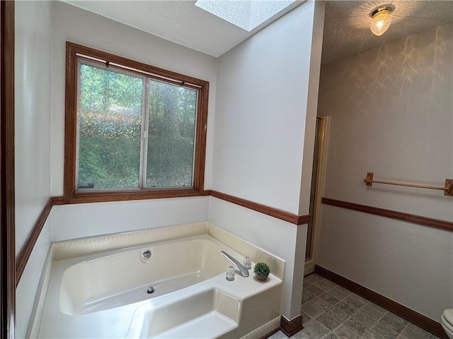 3436 Finglas Dr, Marietta, GA 30008 - full bath featuring a skylight, a bath, baseboards, a textured ceiling, and toilet