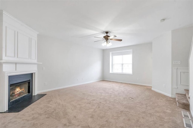 unfurnished living room featuring a large fireplace, light carpet, baseboards, and a ceiling fan