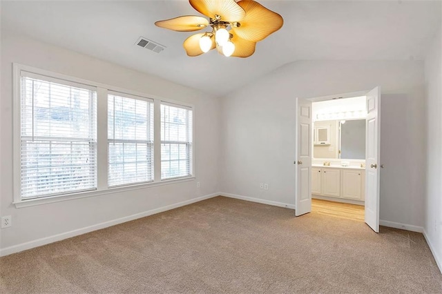 unfurnished bedroom featuring lofted ceiling, light colored carpet, visible vents, and baseboards