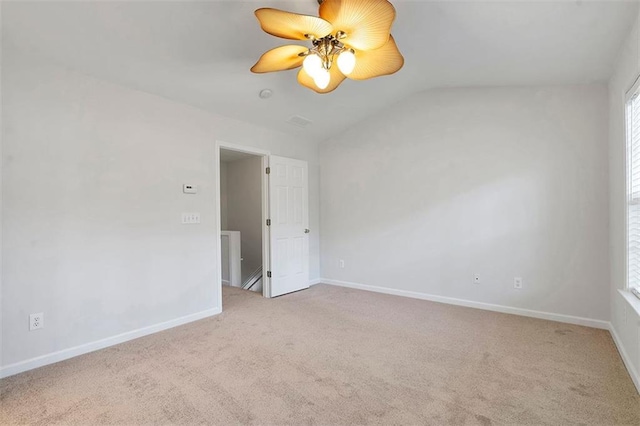 carpeted spare room with lofted ceiling, a ceiling fan, baseboards, and visible vents