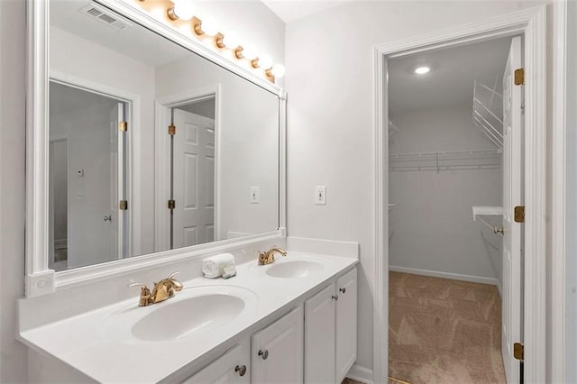 full bath with a sink, visible vents, a spacious closet, and double vanity