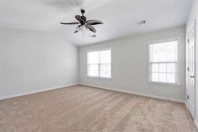 spare room featuring visible vents, light colored carpet, and vaulted ceiling