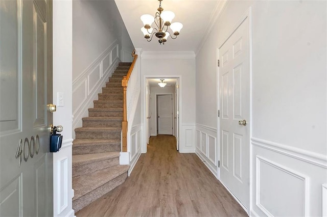 entrance foyer with a decorative wall, stairway, an inviting chandelier, and ornamental molding