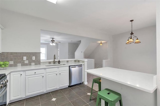 kitchen featuring a sink, a peninsula, white cabinetry, a ceiling fan, and stainless steel dishwasher