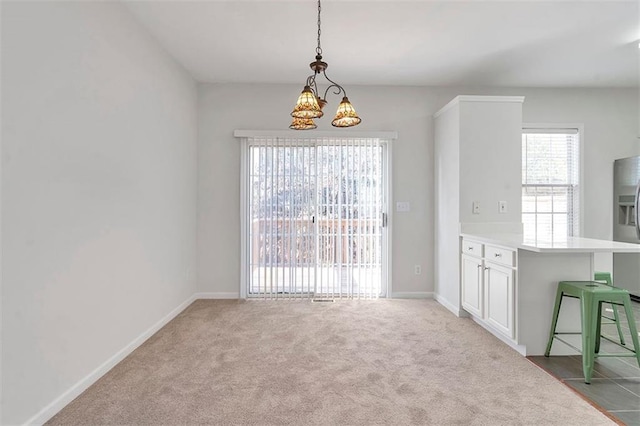 unfurnished dining area with baseboards, an inviting chandelier, and carpet floors