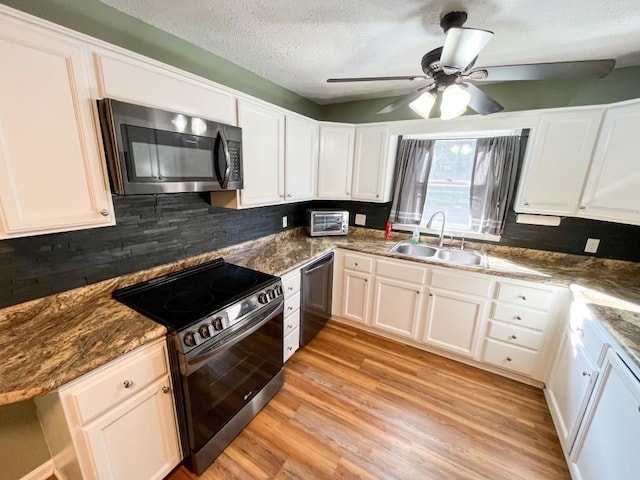 kitchen with sink, appliances with stainless steel finishes, white cabinetry, a textured ceiling, and light wood-type flooring