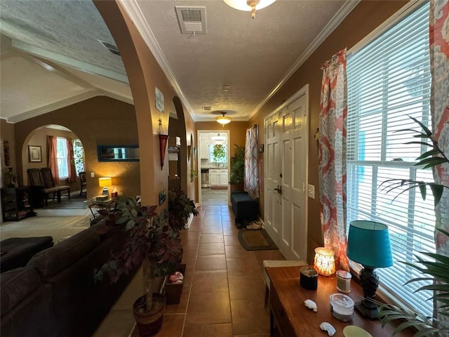 2671 Club Forest Ct SE, Conyers, GA 30013 - hallway featuring arched walkways, tile patterned flooring, a textured ceiling, vaulted ceiling, and crown molding