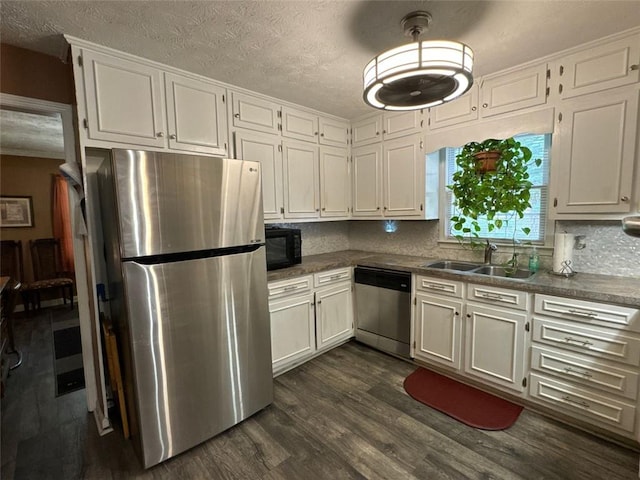 2671 Club Forest Ct SE, Conyers, GA 30013 - kitchen featuring appliances with stainless steel finishes, a sink, dark countertops, white cabinets, and a textured ceiling
