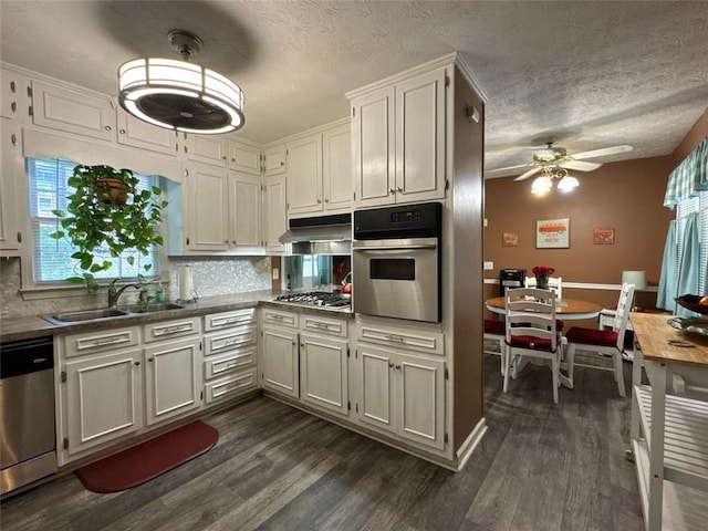 2671 Club Forest Ct SE, Conyers, GA 30013 - kitchen with appliances with stainless steel finishes, a sink, a ceiling fan, dark wood-style floors, and a textured ceiling