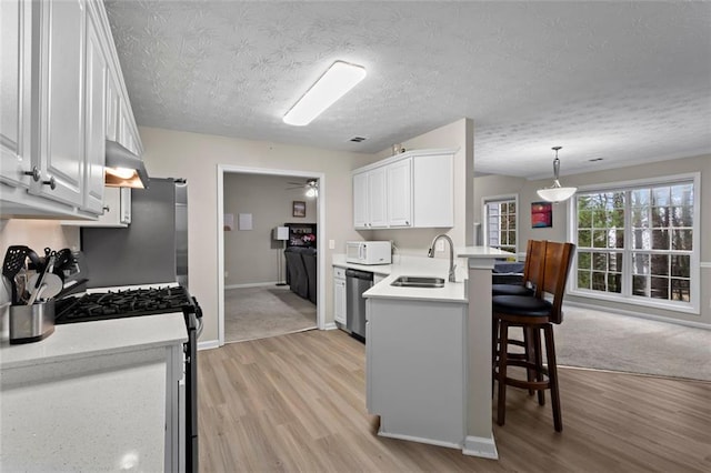 kitchen with white microwave, a sink, a kitchen bar, gas stove, and stainless steel dishwasher