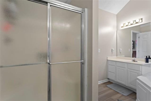 bathroom featuring vanity, a shower stall, wood finished floors, and baseboards