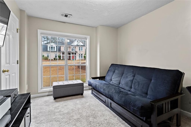 carpeted living room with visible vents, a textured ceiling, and baseboards