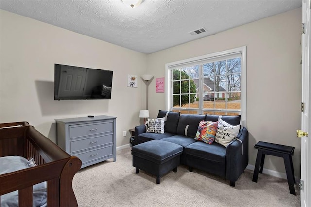 living room with a textured ceiling, light colored carpet, visible vents, and baseboards