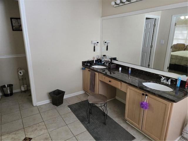 full bath featuring a sink, baseboards, double vanity, and tile patterned floors