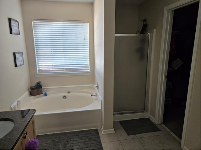 bathroom featuring tile patterned floors, a walk in closet, a garden tub, a stall shower, and vanity