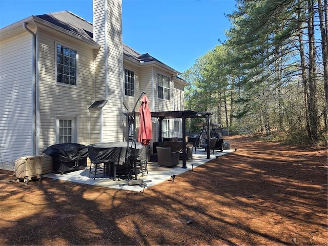 rear view of house with a pergola, a chimney, and a patio area