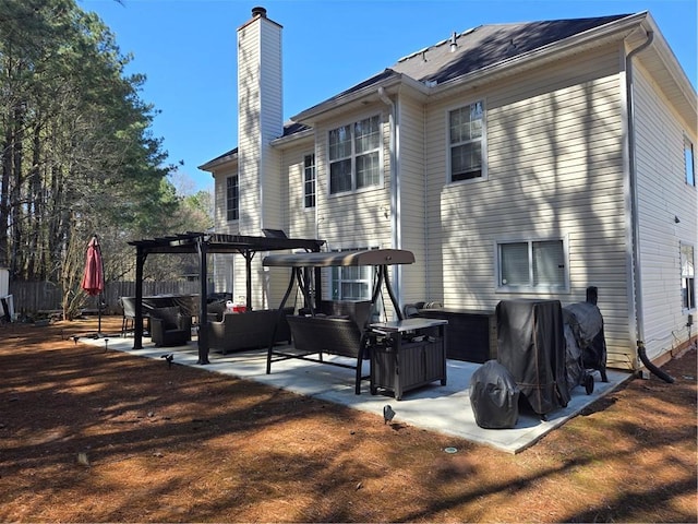 back of property with fence, a chimney, outdoor lounge area, a pergola, and a patio