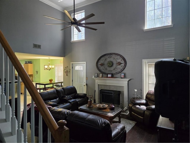 living room featuring visible vents, stairs, ornamental molding, ceiling fan with notable chandelier, and a fireplace