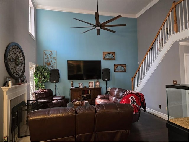 living area with baseboards, a fireplace, ornamental molding, stairs, and a towering ceiling