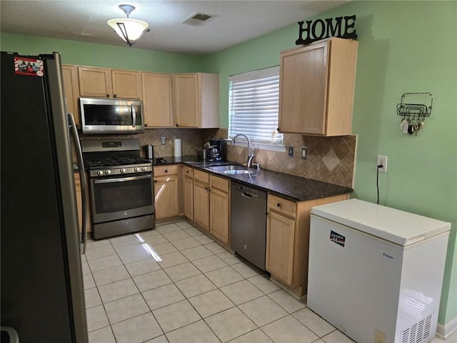 kitchen featuring light brown cabinetry, visible vents, appliances with stainless steel finishes, and a sink