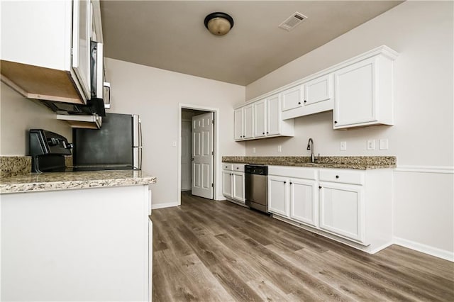 kitchen with light stone countertops, white cabinetry, dark hardwood / wood-style flooring, sink, and stainless steel dishwasher