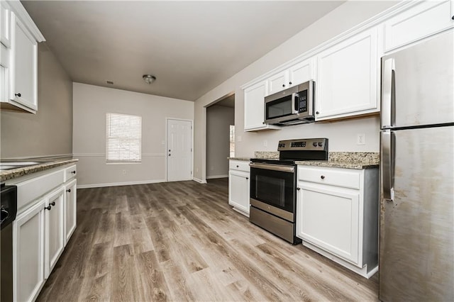 kitchen with light stone counters, white cabinets, light hardwood / wood-style floors, and appliances with stainless steel finishes