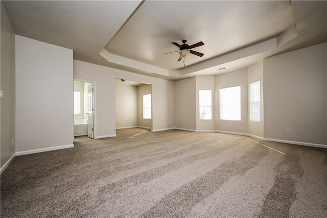 carpeted spare room featuring ceiling fan and a raised ceiling