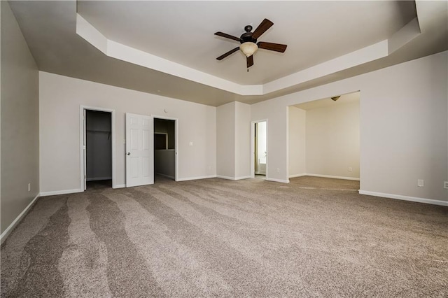 unfurnished bedroom with ceiling fan, carpet, and a tray ceiling