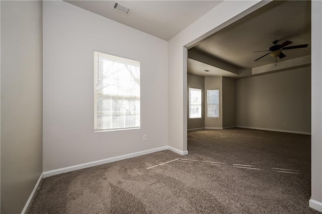 spare room featuring dark colored carpet, plenty of natural light, and ceiling fan