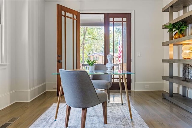 dining space with wood finished floors, visible vents, and baseboards