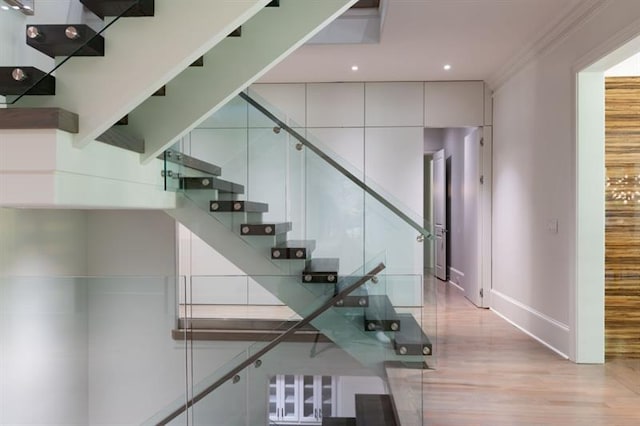 stairs with crown molding, recessed lighting, wood finished floors, and baseboards