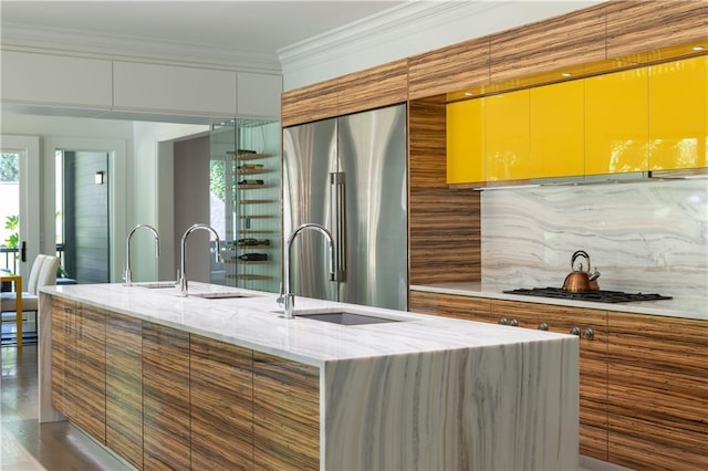 kitchen with gas stovetop, high end fridge, backsplash, ornamental molding, and a sink