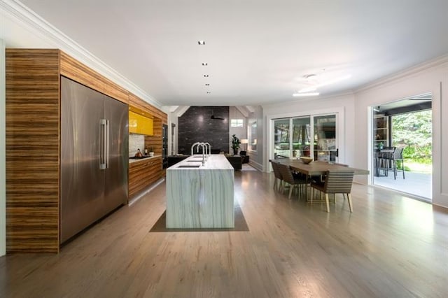 kitchen with high end fridge, light wood finished floors, modern cabinets, and crown molding