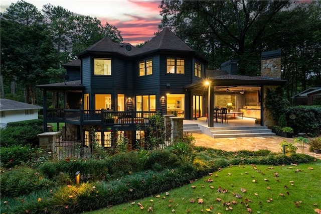 back of house featuring a patio area, a lawn, and a chimney