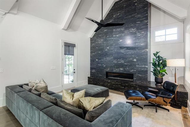 living area with beam ceiling, a premium fireplace, ceiling fan, high vaulted ceiling, and baseboards