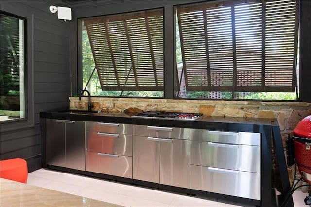 details with wooden walls, stainless steel gas cooktop, and a sink