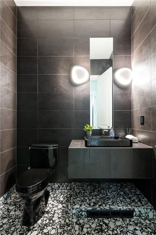 bathroom featuring toilet, tile walls, and vanity