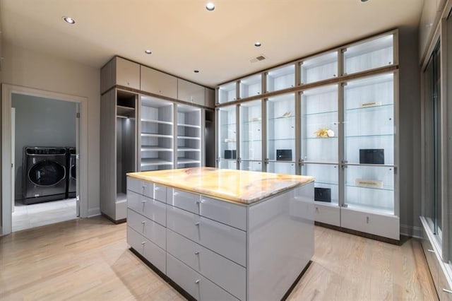 spacious closet with light wood finished floors, visible vents, and washer and dryer