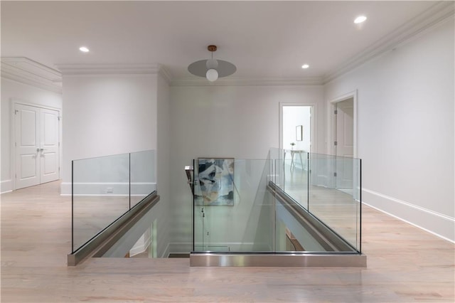 corridor featuring wood finished floors, an upstairs landing, and crown molding