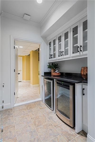 bar featuring beverage cooler, crown molding, and baseboards