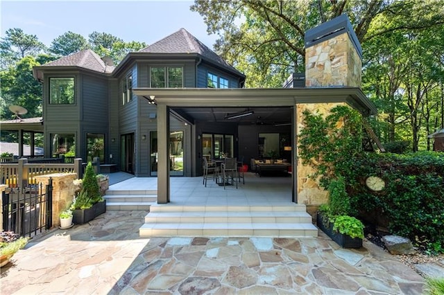 back of property with a chimney, a patio area, and fence