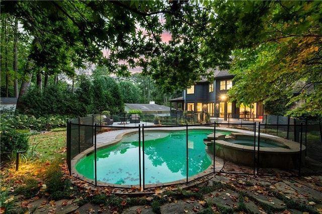 view of swimming pool featuring fence and a pool with connected hot tub