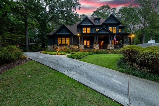 craftsman inspired home featuring stone siding, concrete driveway, covered porch, and a yard