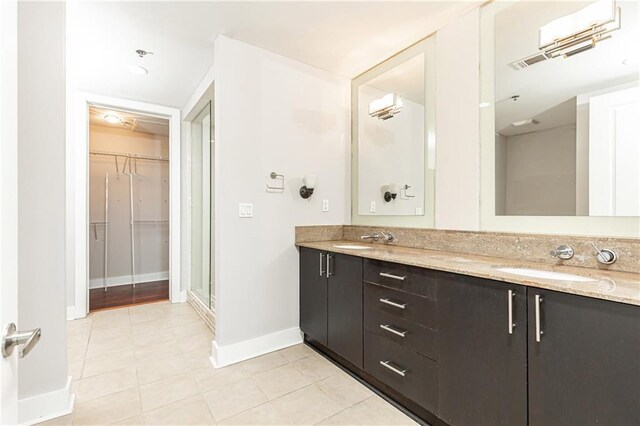 full bath with tile patterned floors, baseboards, double vanity, a spacious closet, and a shower stall