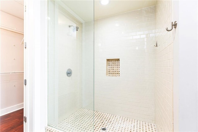 bathroom with a stall shower, wood finished floors, a walk in closet, and recessed lighting