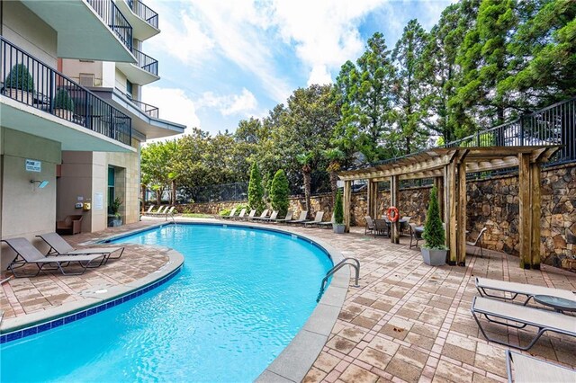 community pool featuring a pergola, a patio area, and fence