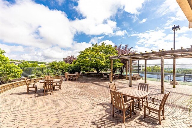 view of patio featuring a tennis court and fence
