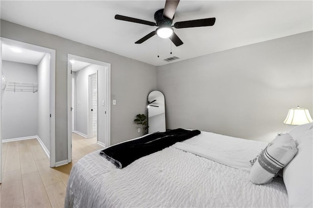 bedroom featuring a spacious closet, ceiling fan, light wood-type flooring, and a closet