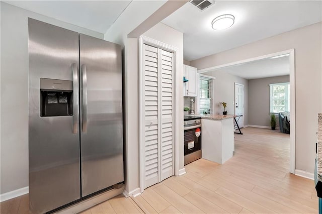 kitchen featuring white cabinets, stainless steel appliances, and light wood-type flooring